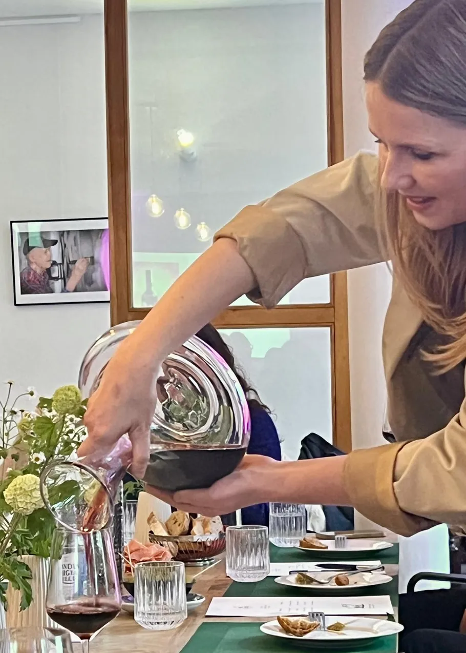 Woman pouring wine into glass at table.