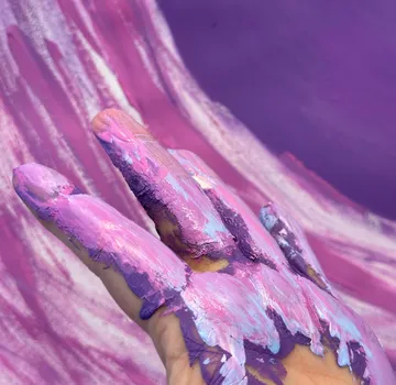 Hand mit lila Farbe, wirbelnde Bewegung.