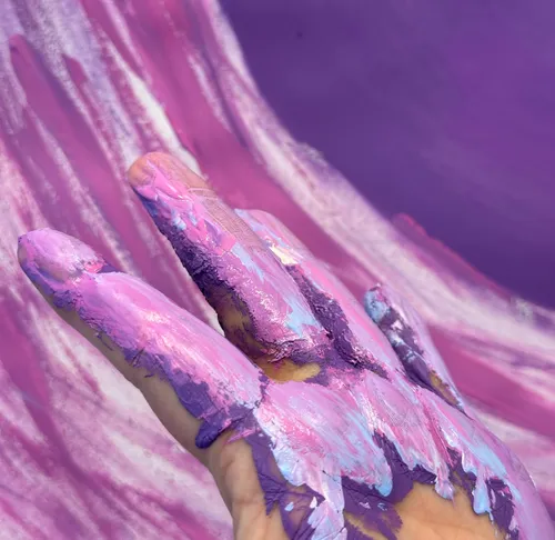 Hand covered in purple paint, swirling motion.