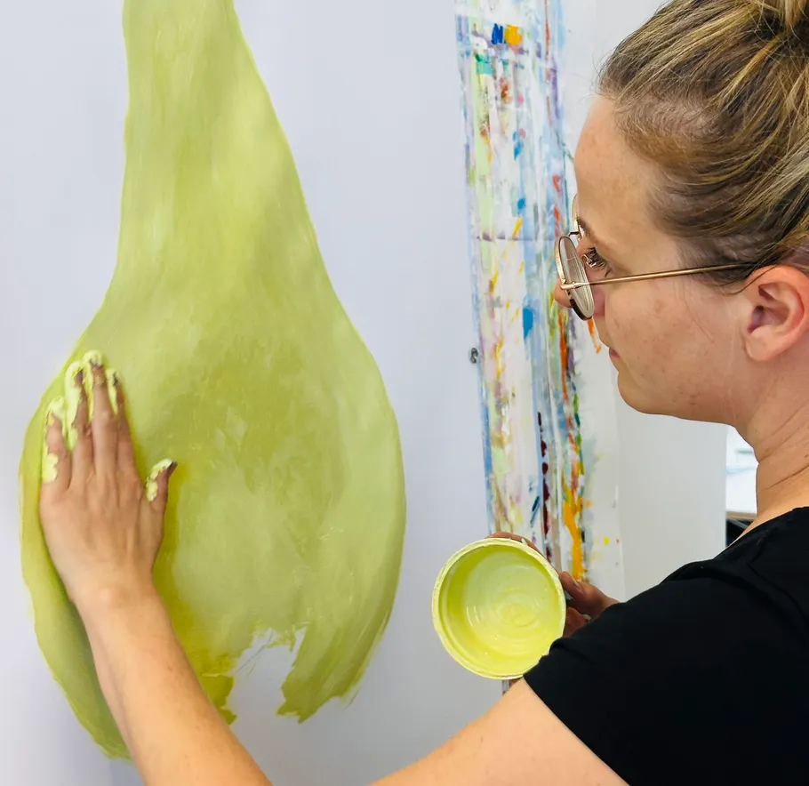 Person trägt grüne Farbe auf Wand auf.