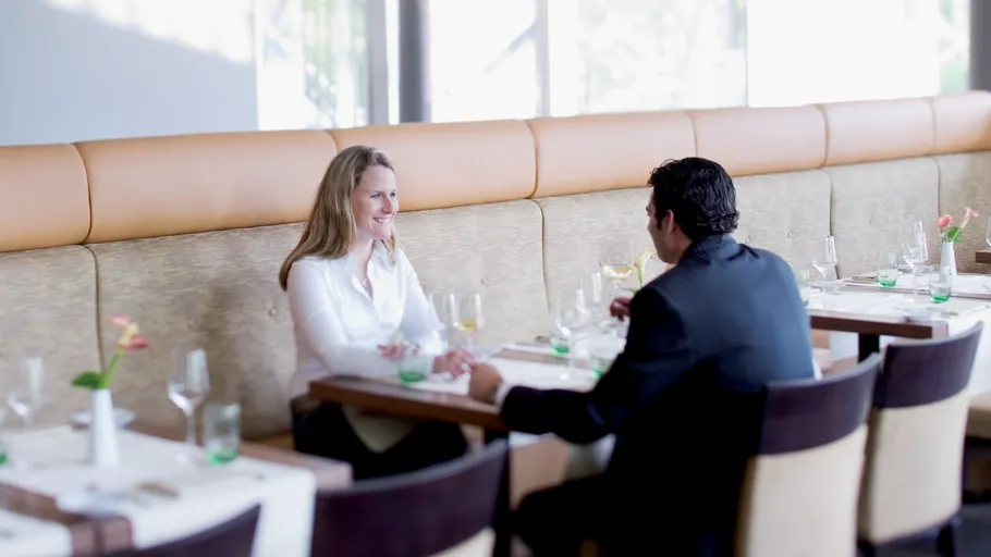 Zwei Personen unterhalten sich in hellem Restaurant.