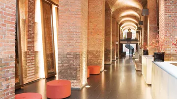 Moderner Lobbybereich mit Backsteinwänden, orange Sitzflächen.