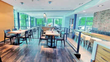 Modernes Restaurant mit Holzboden, Tischen und Stühlen.