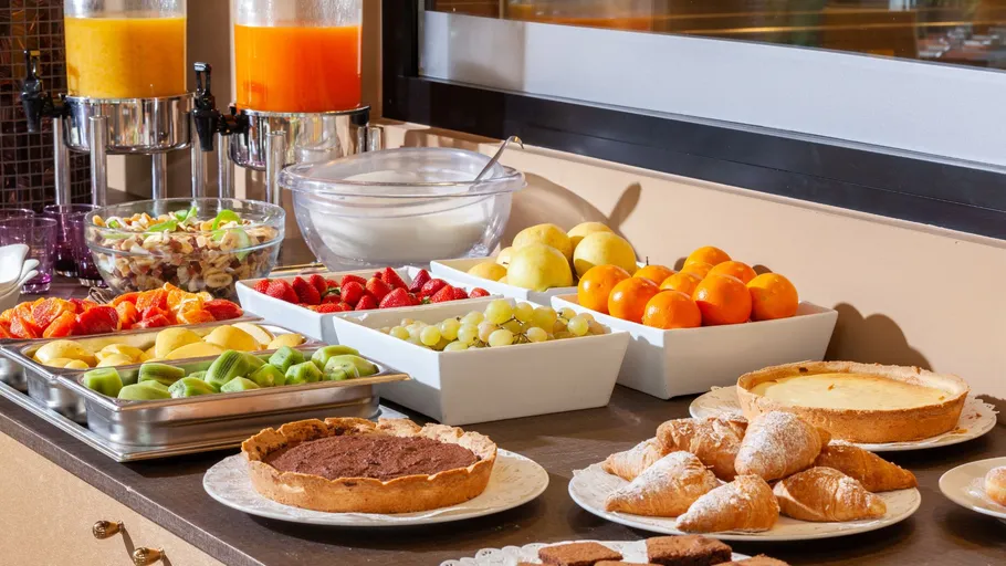 Breakfast buffet with fruits and pastries displayed.