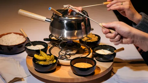 People dipping food in fondue pot.