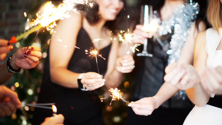 People holding sparklers at a celebration indoors.