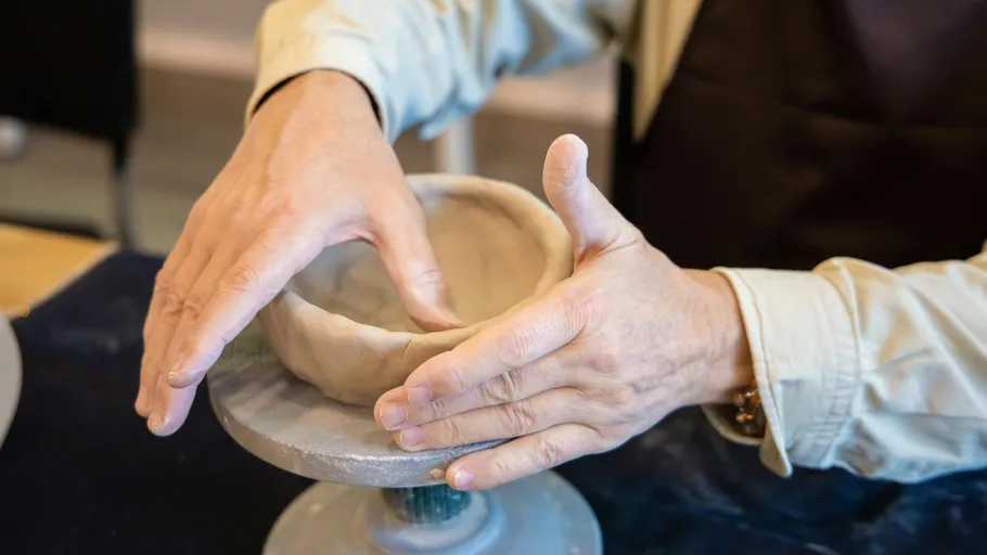 Hands shaping clay on a pottery wheel.