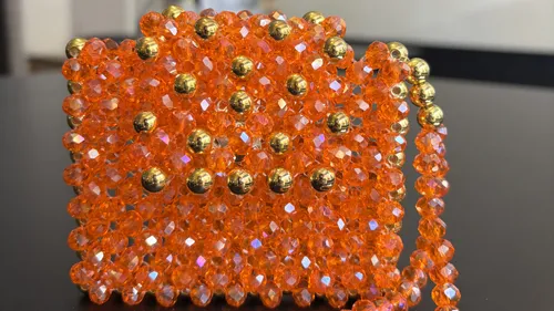 Orange Perlenhandtasche mit goldenen Akzenten drinnen.