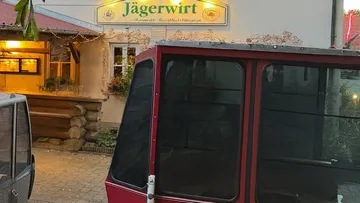 Seilbahnkabinen vor einem Restauranteingang.