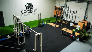 Fitnessstudio mit Geräten und CrossFit-Logo.