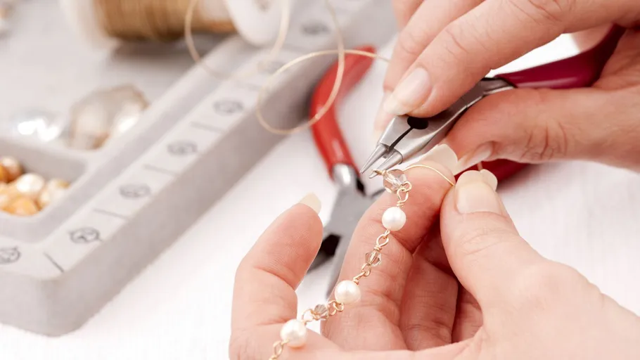 Hands using pliers to make jewelry.