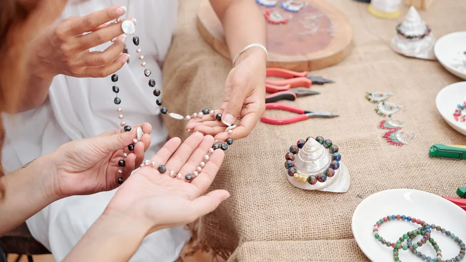 People crafting necklaces on a table.
