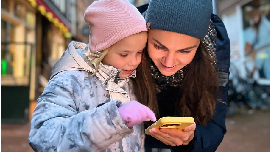 Woman and child smiling, looking at smartphone.