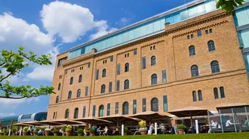 Backsteingebäude mit Außensitzbereich, blauer Himmel.