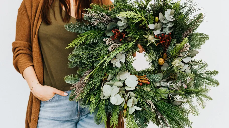 Person holding a green wreath indoors.