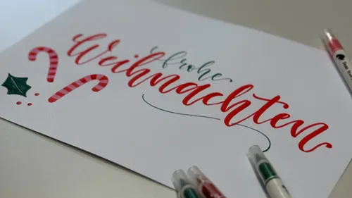 Festliche Karte mit Weihnachtsbeschriftung, Stifte daneben.