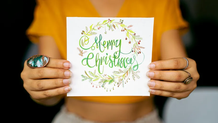 Person hält eine Frohe Weihnachten Karte.