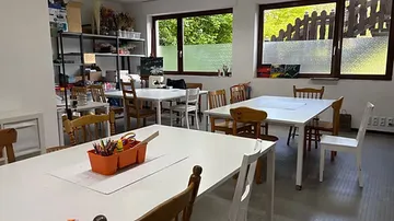 Art classroom with tables, chairs, and supplies.
