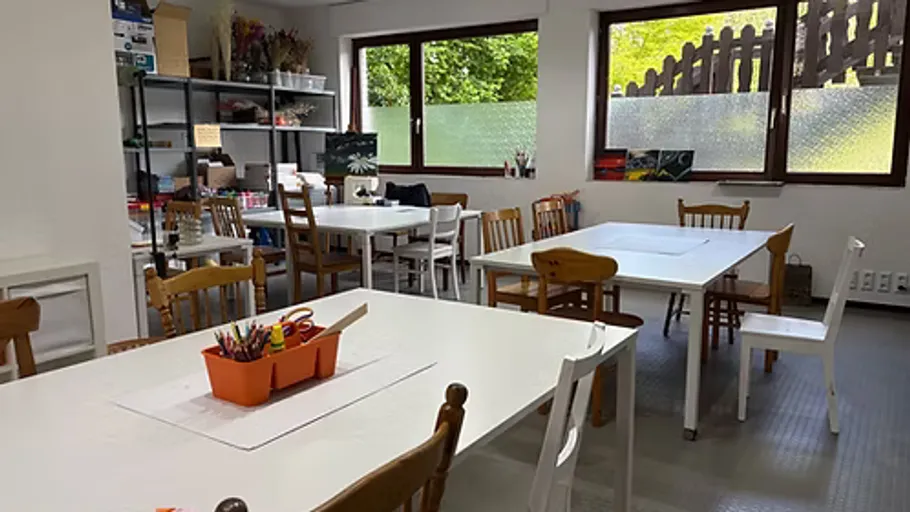 Kunstklassenzimmer mit Tischen, Stühlen und Material.