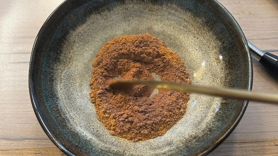 Schüssel enthält braune Gewürzmischung auf Tisch.