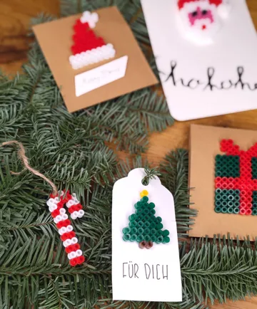 Weihnachtsbasteleien mit Perlen auf Tannenzweigen.