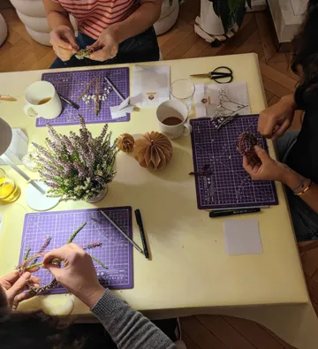 Menschen basteln mit Pflanzen an einem Tisch.