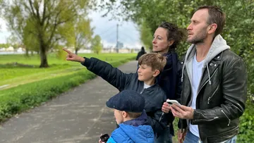 Family pointing skyward on a park path.