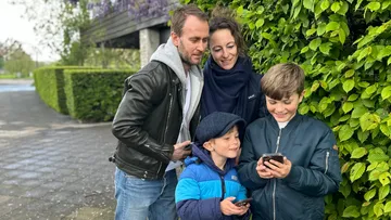 Family outside looking at smartphones.