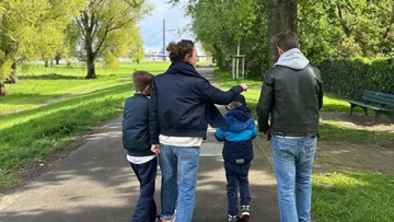 Family walking on path in park.