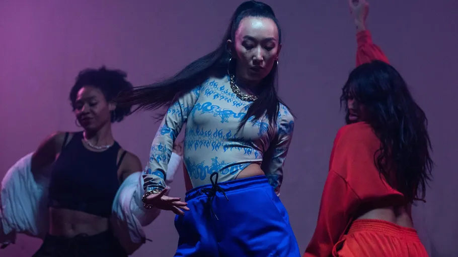 Three women dancing energetically under colorful lights.