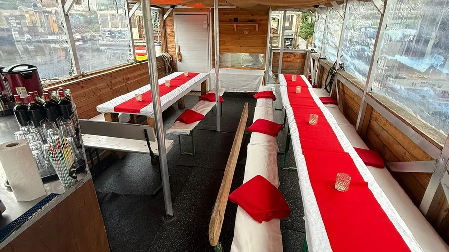 Sitzbereich im Freien mit roten Tischdecken.