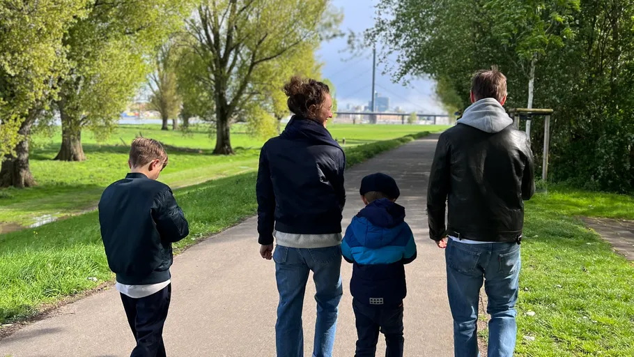 Vier Menschen auf einem baumgesäumten Weg.