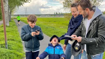 Family walking on riverside path, child excited.