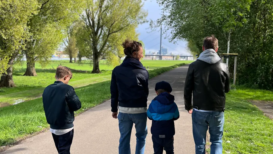 Vier Personen spazieren auf einem Parkweg.