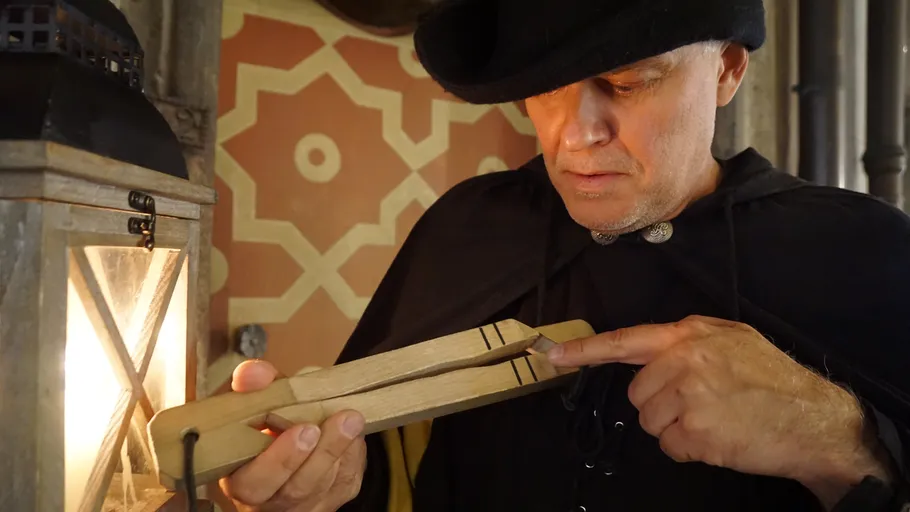 Mann untersucht Holzobjekt neben Laterne drinnen.