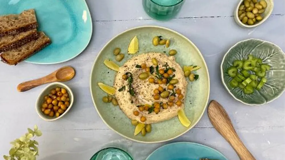 Hummus mit Kichererbsen und Gemüse auf einem Tisch.