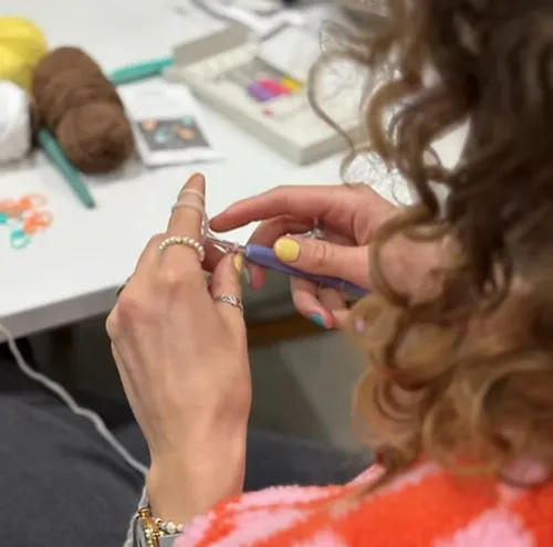 Person crocheting with yarn on a table.