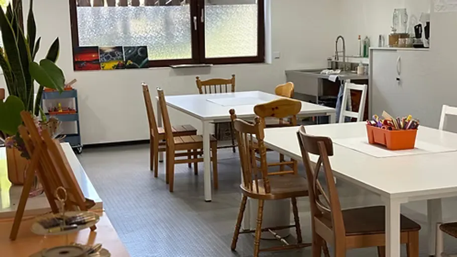 Wooden chairs around white tables in classroom.