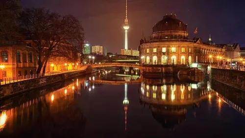 Illuminated building beside river at night.