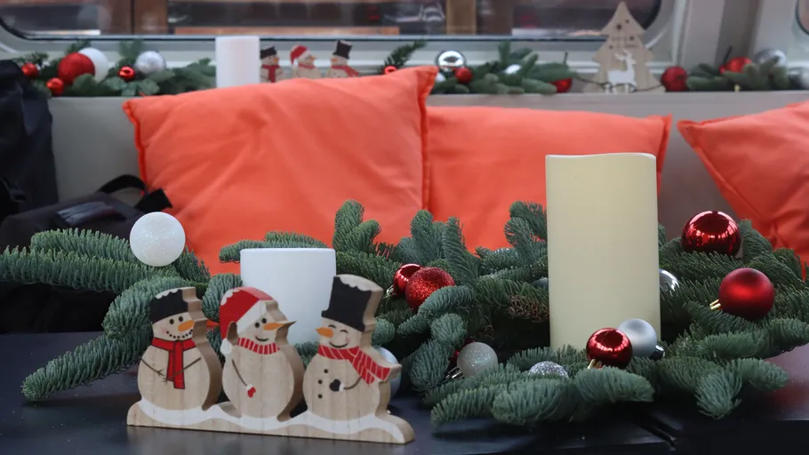 Wood snowmen and candles on festive table.