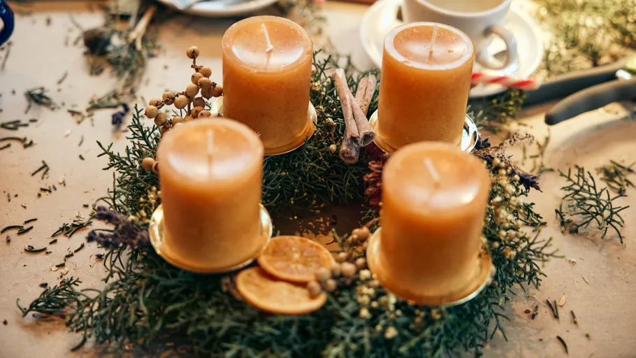 Four candles on a festive wreath table.