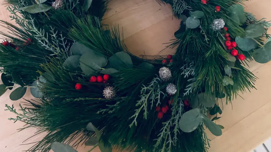 Green wreath with red berries on table.