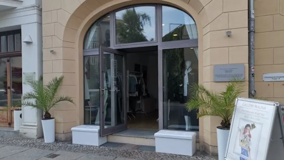 Eingang eines Bekleidungsgeschäfts mit Pflanzen draußen.