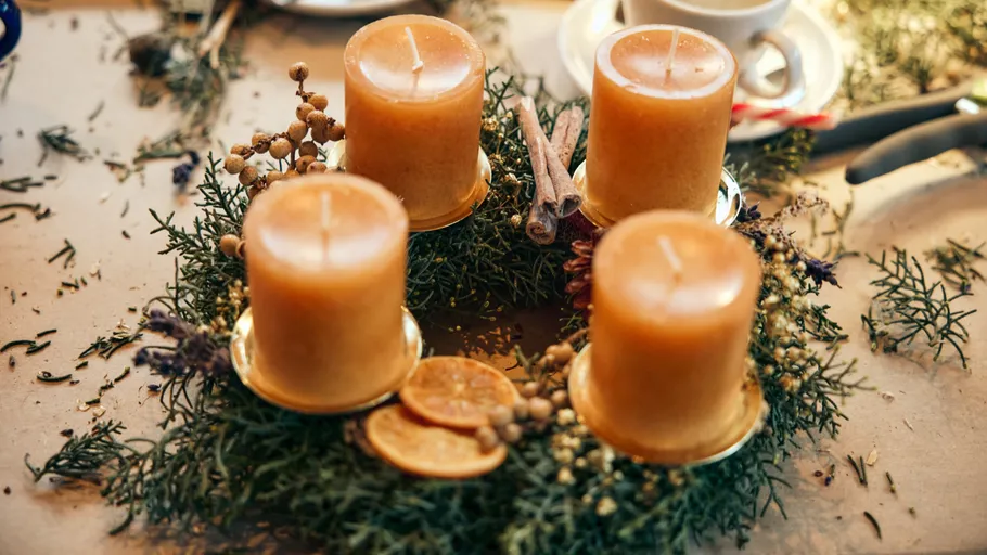 Four candles on a wreath with decorations.