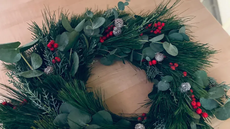 Green wreath with red berries on table.