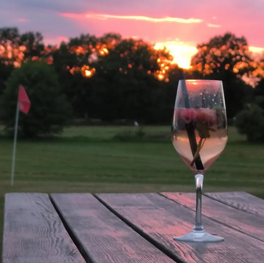 Wine glass on table, sunset in background.