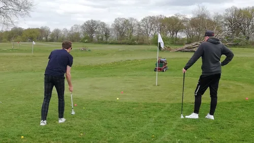 Two golfers preparing to putt on green.