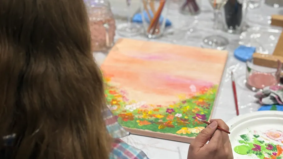 Person painting colorful canvas at workshop.