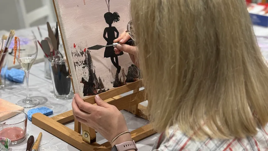 Woman painting silhouette on canvas easel.
