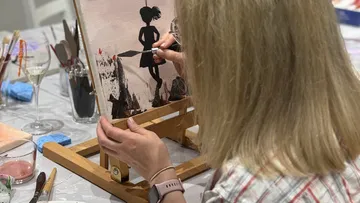 Frau malt Silhouette auf Leinwand im Studio.
